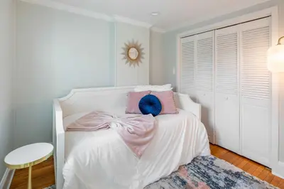 a bedroom with a white bed with pink and blue pillows at Brooke House In The Heart of Downtown with Patio! in Lambertville