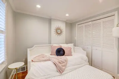 a bedroom with a white bed with pink pillows at Brooke House In The Heart of Downtown with Patio! in Lambertville