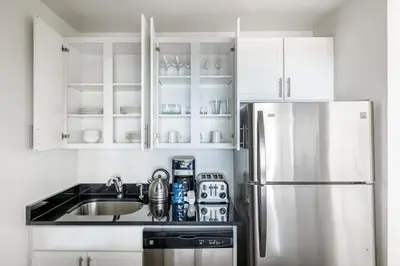 a kitchen with white cabinets and a stainless steel refrigerator at UWS 1BR w Doorman Gym Parking nr Central Park NYC-596 in New York