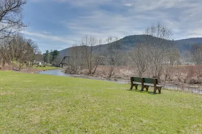 a park bench sitting in the grass next to a river at Scenic Home on the Delaware River, Pet-Friendly! in Starlight