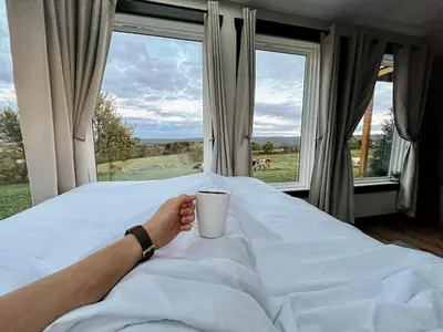 a person laying on a bed with a cup of coffee at ‘Scenic Escapes’ Romantic Pine Grove Getaway! in Pine Grove