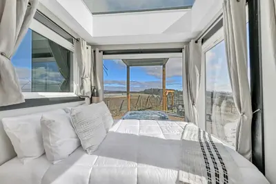 a white bed in a room with a large window at ‘Scenic Escapes’ Romantic Pine Grove Getaway! in Pine Grove