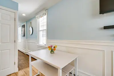 a white table with a vase of flowers on it at New Jersey Abode - Near Theme Parks, Walk to Beach in Keansburg