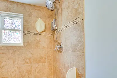 a bathroom with a shower with a toilet and a window at New Jersey Abode - Near Theme Parks, Walk to Beach in Keansburg