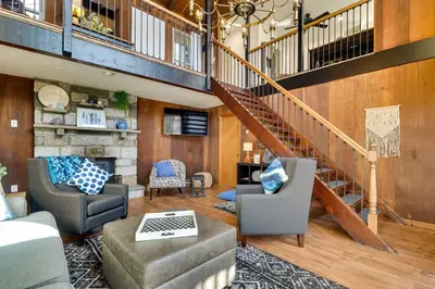 a large living room with a staircase and chairs at Dock and Fire Pit Lakefront Poconos Retreat! in Long Pond