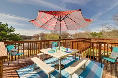 a table and chairs on a deck with an umbrella at Dock and Fire Pit Lakefront Poconos Retreat! in Long Pond