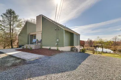 a green house with a gravel driveway at Dock and Fire Pit Lakefront Poconos Retreat! in Long Pond