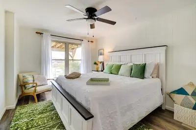 a bedroom with a large bed with a ceiling fan at Dock and Fire Pit Lakefront Poconos Retreat! in Long Pond