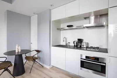 a kitchen with white cabinets and a table with chairs at Midtown 1br w doorman gym wd nr Rock Center NYC-1131 in New York