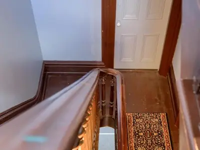 a hallway with a staircase with a door and a rug at Shamokin Bed and Breakfast in Shamokin