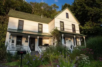 an old white house with flowers in the yard at The Yarra in Roscoe
