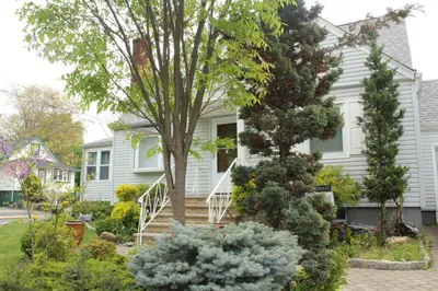 a white house with a tree and some bushes at Beautiful place minutes away to New York City . in Teaneck