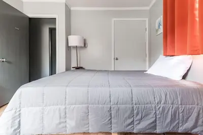 a bedroom with a large white bed with an orange curtain at Waterfront Stagshead Lakehouse at Lake Arrowhead in Arrowhead Lake