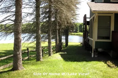 a side view of a home with trees and a fence at Waterfront Stagshead Lakehouse at Lake Arrowhead in Arrowhead Lake