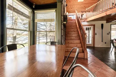 a large wooden table in a room with a staircase at Waterfront Stagshead Lakehouse at Lake Arrowhead in Arrowhead Lake