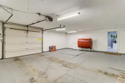 an empty garage with two garage doors and a chair at 7 Mi to Whitewater Rafting Cozy Lansford Cabin! in Barnesville