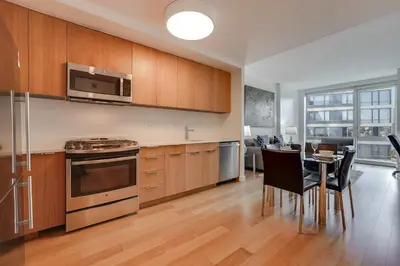 a kitchen with wooden cabinets and a table with chairs at Global Luxury Suites at Via 57 in New York