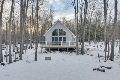 a small white house in the woods in the snow at Hike and Ski Pocono Lake Home with Community Perks! in Pocono Lake