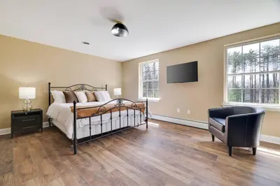 a bedroom with a bed and a tv and a chair at Luxe Lrg Pocono House for 18 Hot Tub/Gameroom/Pool in Kunkletown