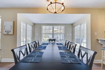 a dining room with a long table with chairs and a chandelier at Luxe Lrg Pocono House for 18 Hot Tub/Gameroom/Pool in Kunkletown