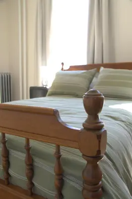 a bed with a wooden foot board in a bedroom at Charming Victorian Home In Historic District in Newburgh