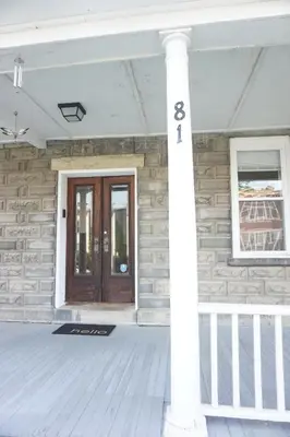 a front porch of a house with a wooden door at Charming Victorian Home In Historic District in Newburgh