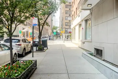 a sidewalk with cars parked on a city street at Midtown E Studio w Great light Gym NYC-139 in New York