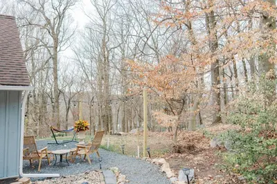 a patio with a table and chairs in the woods at Cowry Acres - 11 Acre Enchanted Retreat, Hot Tub in New Hope