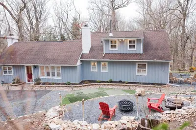 a blue house with red chairs in a yard at Cowry Acres - 11 Acre Enchanted Retreat, Hot Tub in New Hope