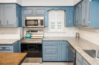 a blue kitchen with white appliances and blue cabinets at Cowry Acres - 11 Acre Enchanted Retreat, Hot Tub in New Hope