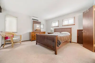 a bedroom with a bed and a chair and windows at Camelback Condo in Tannersville