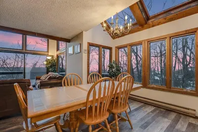 a dining room with a table and chairs and windows at Camelback Condo in Tannersville