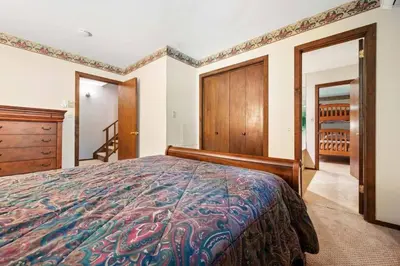 a bedroom with a bed and a dresser and a staircase at Camelback Condo in Tannersville