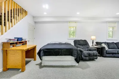 a bedroom with a bed and two chairs and a staircase at Walk to Lake Wallenpaupack Poconos Vacation Home in Lake Ariel